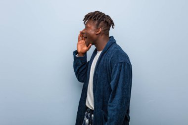 Genç Afrikalı siyah adam pijama giymiş bağırıyor ve avuç içini açık tutuyor..