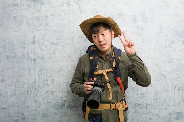 Jovem Chinês Explorador Homem Segurando Uma Câmera Mostrando Número Dois — Fotografia de Stock