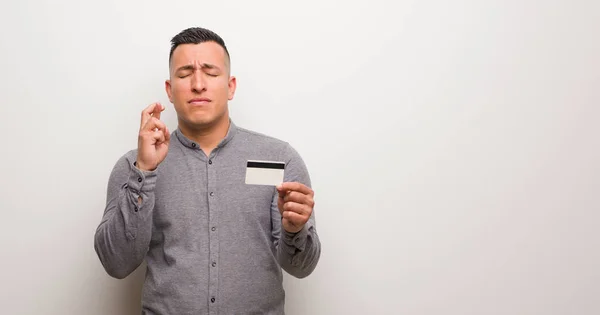 Joven Latino Sosteniendo Una Tarjeta Crédito Cruzando Dedos Para Tener — Foto de Stock