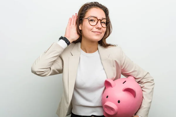 Jovem Mulher Negócios Europeia Segurando Banco Porquinho Tentando Ouvir Uma — Fotografia de Stock