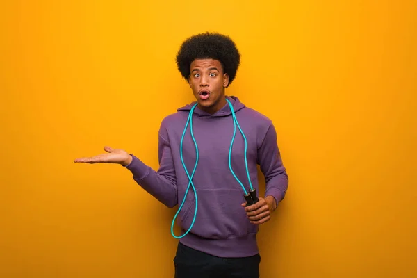 ヤシの手に何かを保持するジャンプロープを保持する若いアフリカ系アメリカ人のスポーツマン — ストック写真