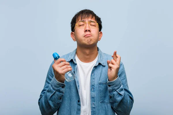 Joven Chino Sosteniendo Una Botella Agua Cruzando Los Dedos Para —  Fotos de Stock