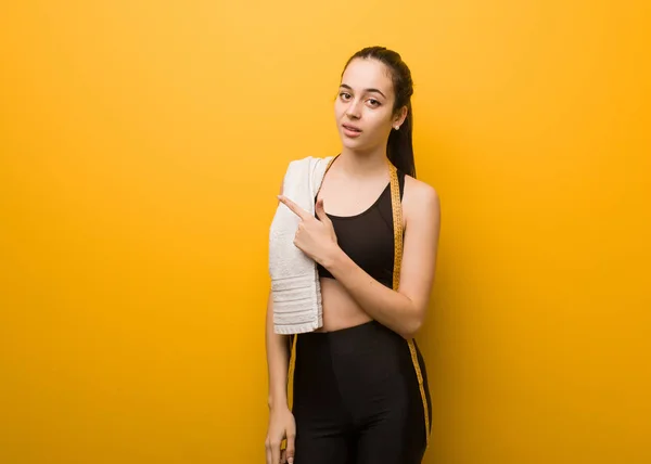 Young fitness girl smiling and pointing to the side