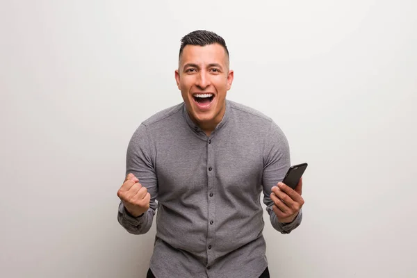 Mladý Latinský Muž Drží Telefon Překvapený Šokovaný — Stock fotografie
