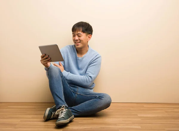Junger Chinese Sitzt Mit Seinem Tablet Und Lächelt Selbstbewusst Verschränkt — Stockfoto