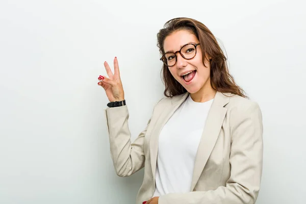 Young european business woman joyful and carefree showing a peace symbol with fingers.