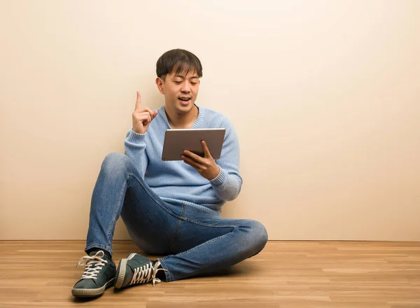 Young Chinese Man Sitting Using His Tablet Surprised Pointing Show — 图库照片