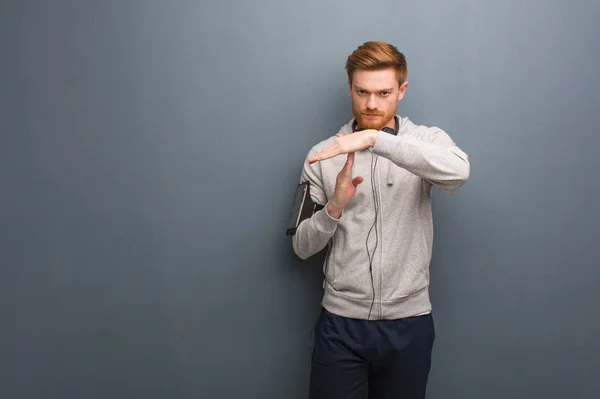 Young fitness redhead man doing a timeout gesture