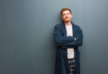 Pijamalı genç kızıl adam yorgun ve sıkılmış.