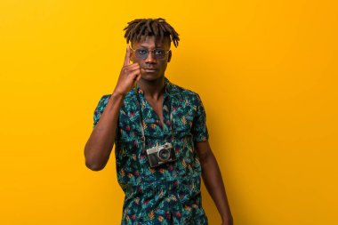 Tatil giymiş genç siyah Rasta adam parmağıyla bir numarayı gösteriyor..