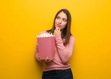 Elinde patlamış mısır kovası tutan genç ve güzel bir kadın.