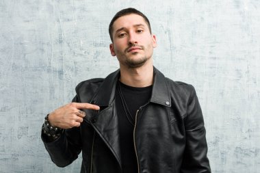 Genç rockçı adam bir gömlek fotokopi alanını elle gösteriyor, gururlu ve kendinden emin.