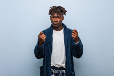 Genç Afrikalı siyah adam pijama giyiyor ve parasız olduğunu gösteriyor..