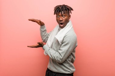 Genç fitness Afrikalı Zenci adam şok oldu ve hayrete düştü ellerinin arasında bir kopya alanı tutuyor.