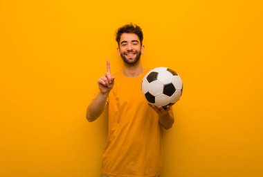 Genç futbolcu bir numarayı gösteriyor.
