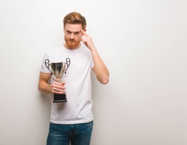 Genç kızıl adam bir fikir düşünüyor. Elinde bir kupa.