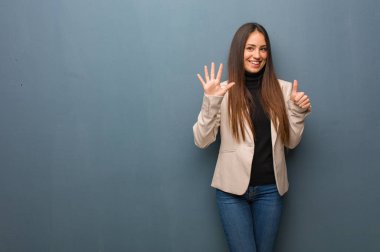 Altı numarayı gösteren genç bir iş kadını.