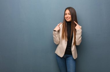 Genç iş kadını gülümsüyor, ağzını işaret ediyor.