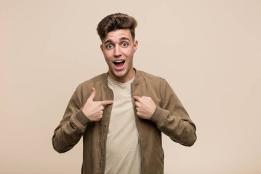 Kahverengi ceketli genç beyaz adam kendini işaret ederek, geniş bir gülümsemeyle şaşırdı..