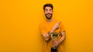 Elinde bir kupa tutan genç adam gülümsüyor ve yan tarafı gösteriyor.