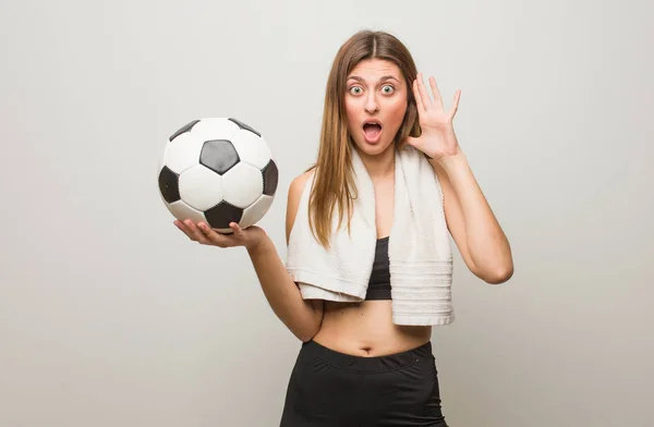 Młoda Fitness Rosyjska Kobieta Zaskoczony Zszokowany Trzymanie Piłki Nożnej — Zdjęcie stockowe