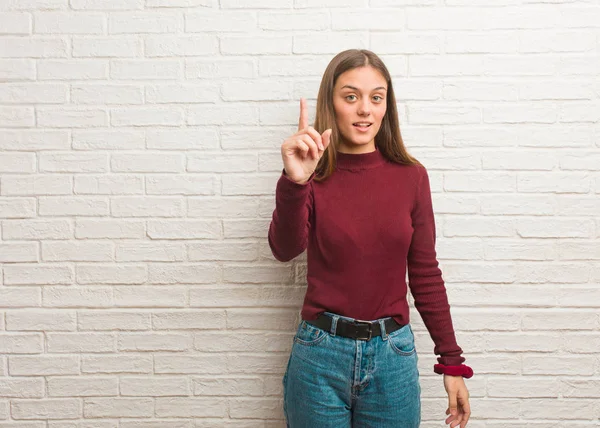 Young cool woman over a bricks wall showing number one