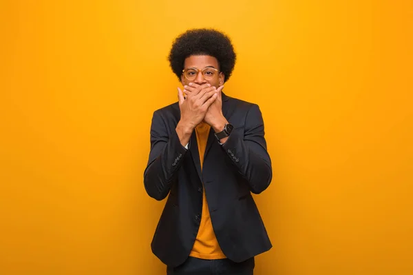 Young business african american man over an orange wall surprised and shocked