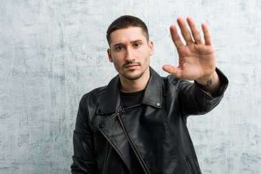 Genç rockçı elini uzatıp dur işareti göstererek seni engelliyor..