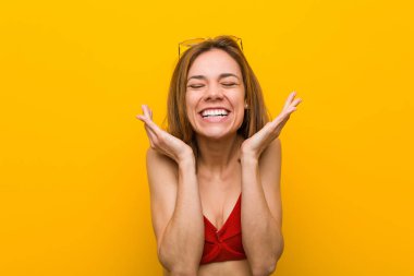 Young caucasian woman wearing bikini and sunglasses joyful laughing a lot. Happiness concept.