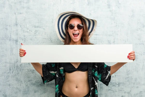Ung europeisk kvinna som bär bikini och håller i en skylt — Stockfoto