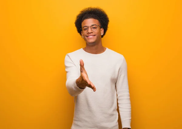 Jovem Homem Afro Americano Sobre Uma Parede Laranja Estendendo Mão — Fotografia de Stock