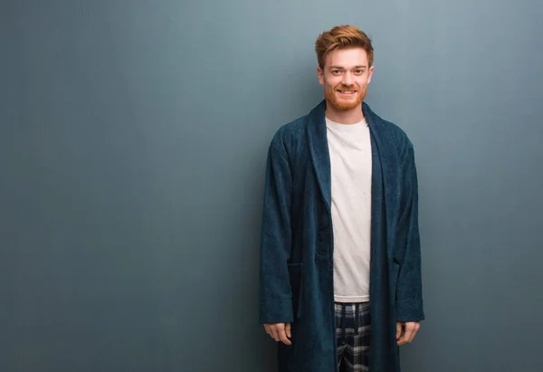 Young redhead man in pajama cheerful with a big smile
