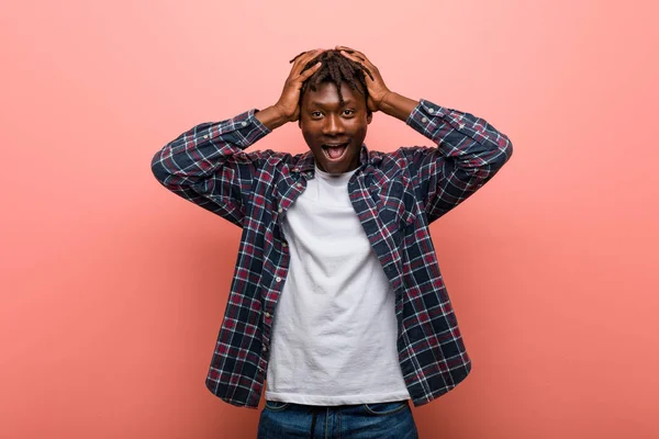 Young african black man laughs joyfully keeping hands on head. Happiness concept.