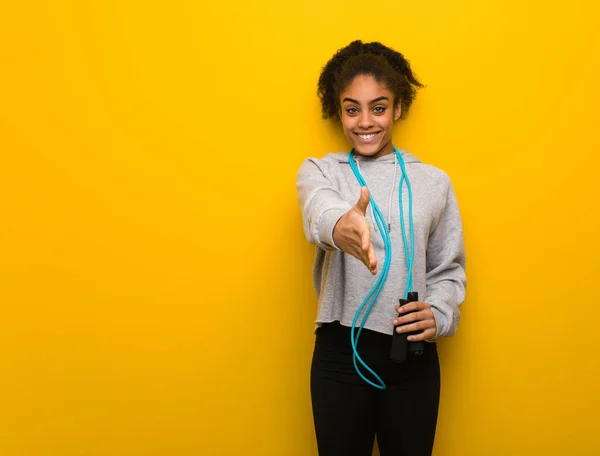 Young fitness black woman reaching out to greet someone. Holding a jump rope.