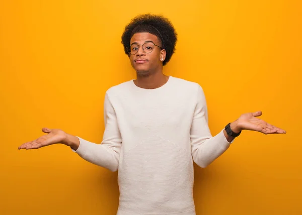 Giovane Uomo Afroamericano Sopra Muro Arancione Che Dubita Scuote Spalle — Foto Stock
