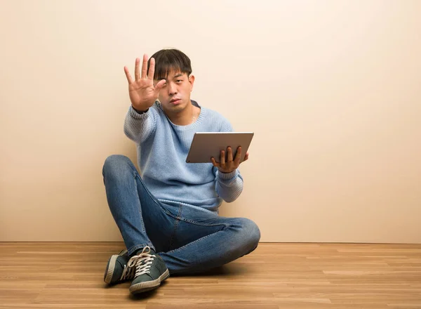 Jovem Chinês Sentado Usando Seu Tablet Colocando Mão Frente — Fotografia de Stock