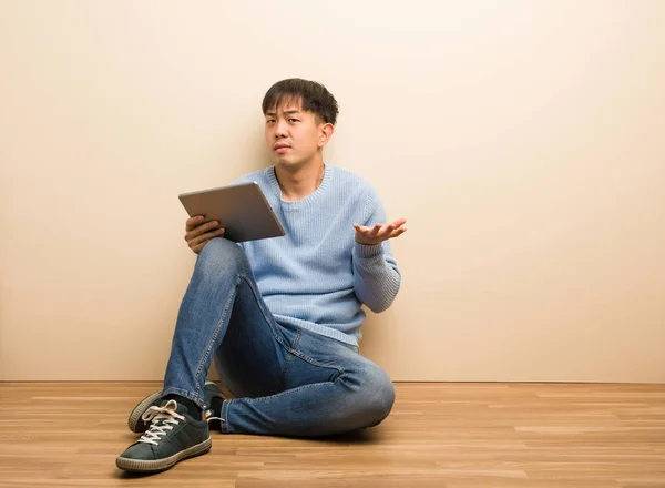 Jovem Chinês Sentado Usando Seu Tablet Confuso Duvidoso — Fotografia de Stock