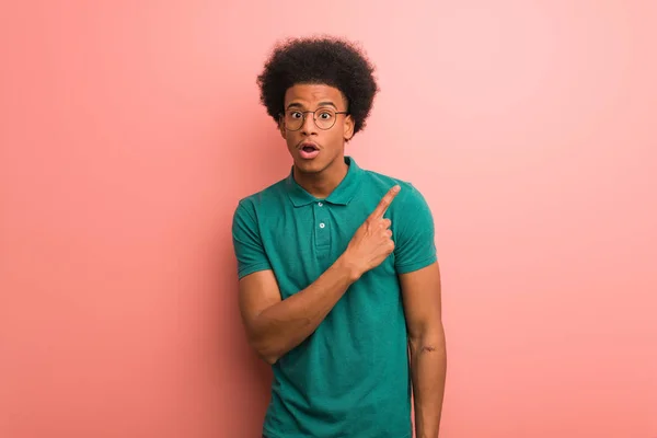 Joven Afroamericano Sobre Una Pared Rosa Apuntando Hacia Lado — Foto de Stock