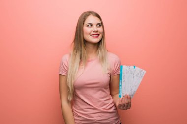 Genç, güzel Rus kız kendine güvenen ve kollarını kavuşturup yukarı bakıyor. Elinde uçak bileti var..