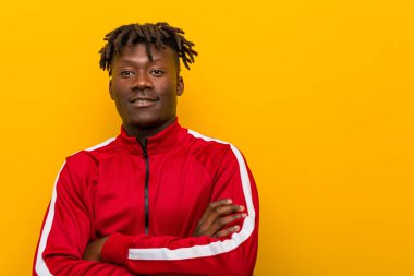Genç fitness Afrikalı adam kollarını kavuşturarak gülümsüyor..