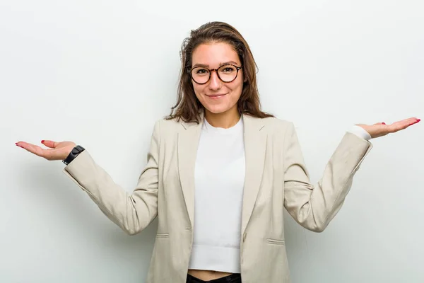 Young european business woman doubting and shrugging her shoulders in questioning gesture.