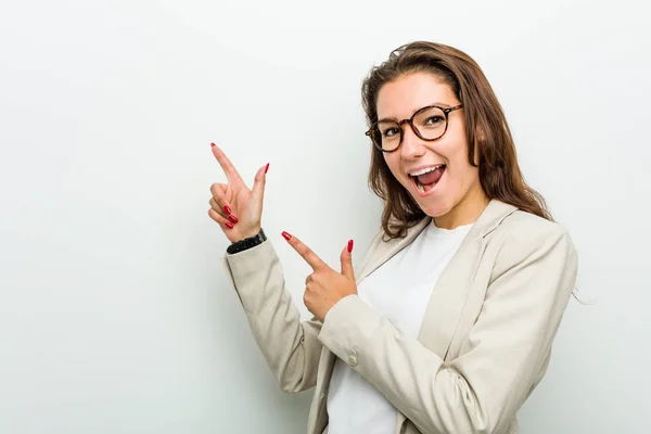 Young european business woman pointing with forefingers to a copy space, expressing excitement and desire.