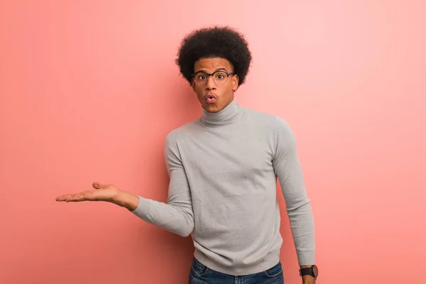 Jovem Afro Americano Sobre Uma Parede Cor Rosa Segurando Algo — Fotografia de Stock