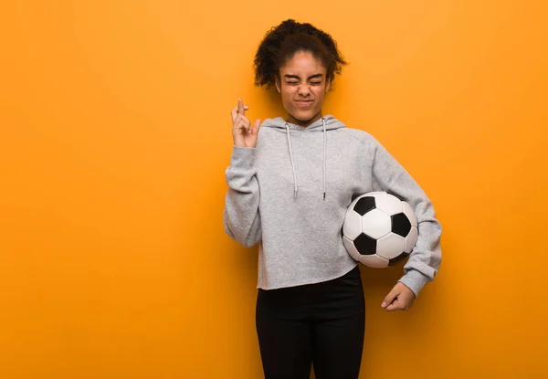年轻健康的黑人女子因运气好而交叉手指 拿着足球 — 图库照片