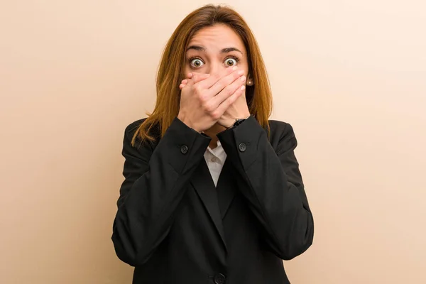 Young caucasian business woman shocked covering mouth with hands.