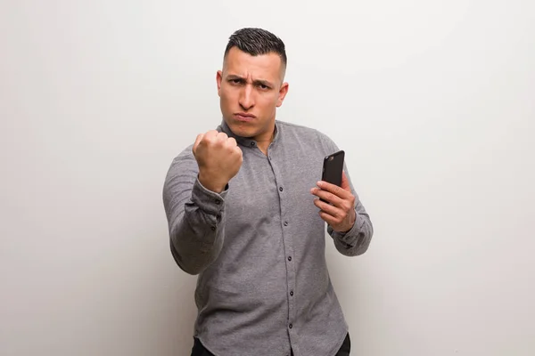 Jovem Latino Segurando Telefone Mostrando Punho Para Frente Expressão Irritada — Fotografia de Stock