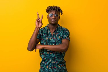 Tatil giymiş genç siyah Rasta adam iki numarayı parmaklarıyla gösteriyor..