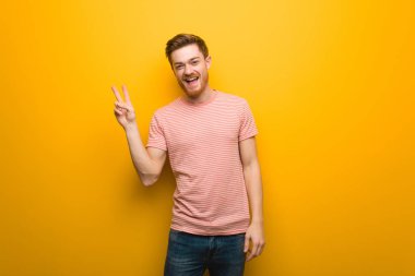 Genç kızıl saçlı adam zafer jesti yapıyor