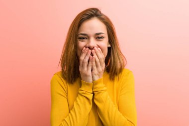 Young pretty young woman laughing about something, covering mouth with hands.