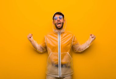 Yağmurluk giyen genç adam çok sinirli ve agresif bağırıyor.